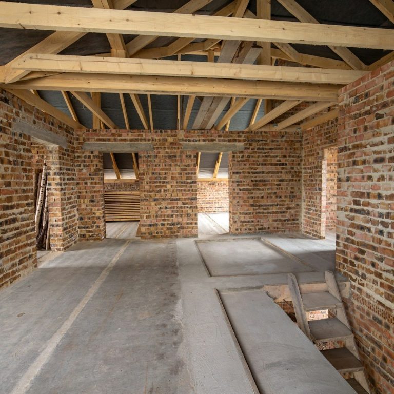 Rohbau eines Hauses mit sichtbaren Ziegelwänden und Holzrahmen.